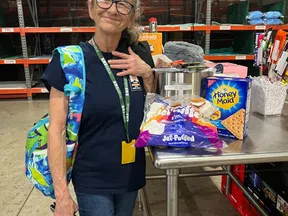 Smiling woman standing in warehouse with marshmallows and graham crackers on metal table for s'mores making.