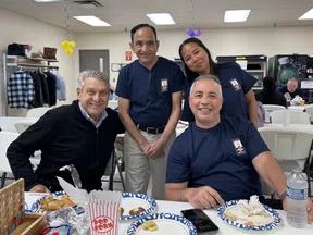 Four diverse coworkers smiling and enjoying snacks at a casual office gathering with balloons and games.