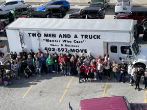 a group of people standing next to a large white truck