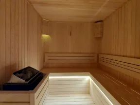Spacious wooden sauna interior with bench seating and modern lighting under the benches.