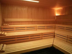 Interior of a wooden sauna with tiered benches and warm ambient lighting along the walls.