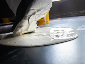 Close-up of wet white paint pouring onto a dark surface during a painting or renovation project.