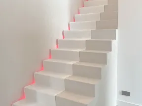 White modern staircase with unique fabric runner and subtle red LED lighting along the wall edge.