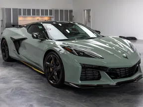Gray Chevrolet Corvette sports car with black wheels parked indoors on a polished concrete floor.