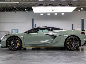 Side view of a sleek gray sports car with black and yellow accents parked in a modern garage.