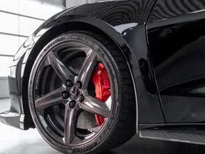 Close-up of a high-performance sports car wheel with carbon fiber rim and red brake caliper.