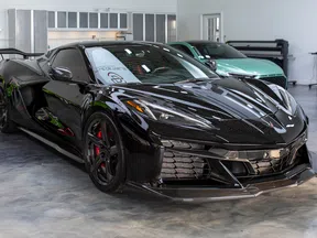 Sleek black sports car parked indoors showcasing aggressive design and polished finish under showroom lights