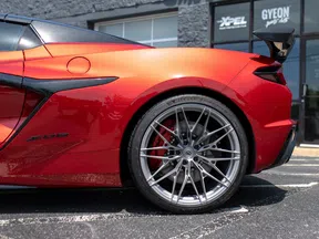 Close-up of rear side of shiny red sports car showing sleek design and large silver alloy wheel.