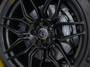 Close-up of a black forged Corvette car wheel with detailed brake caliper and tire tread.