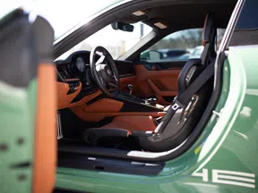 Interior view of a green sports car showing black and tan leather seats, steering wheel, and dashboard.