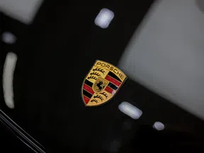 Close-up of the Porsche emblem on a shiny black car hood with light reflections.