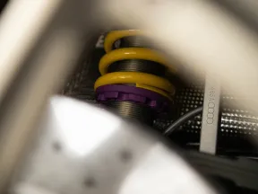 Close-up of a yellow coil spring and purple suspension component within an Audi car chassis.