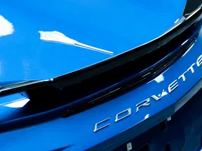 Close-up of blue Corvette car rear with chrome Corvette lettering and sleek black spoiler detail