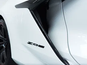 Close-up of a white sports car side panel with Z06 badge and black rear wheel in a garage setting.
