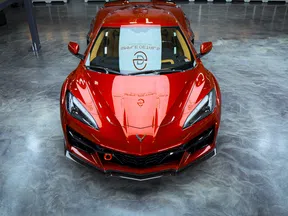 Shiny red sports car with sleek design displayed on polished concrete showroom floor under bright lighting.