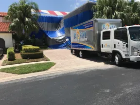 Royal Pest & Termite truck parked outside a home tented for pest control with blue and white coverings