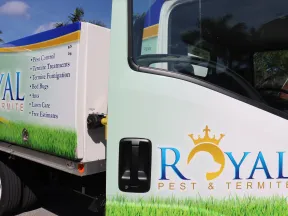 Royal Pest & Termite service truck with logo and list of pest control services parked outdoors under blue sky.