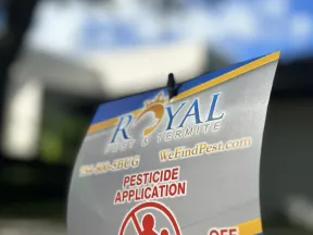 Royal Pest & Termite pesticide application warning sign advising to keep off treated area outdoors.