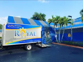 Royal Pest & Termite truck parked near a blue and gray tent for termite fumigation with palm trees around.