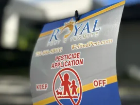 Royal Pest & Termite pesticide application sign advising to keep off treated area with icons of people and pets.