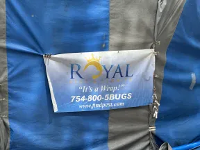 Royal Pest & Termite banner on blue and gray protective wrap with contact number and website.