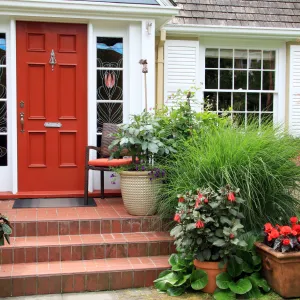 a red door and potted plants outside a house