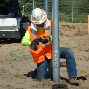 a person wearing a safety vest and holding a pipe
