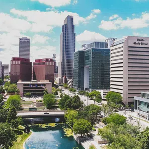 Downtown Omaha skyline with modern skyscrapers, green park area, and blue sky with clouds on a clear day