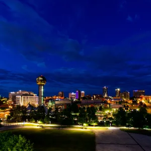 Nighttime skyline of Knoxville, Tennessee with illuminated Sunsphere tower and city lights under a deep blue sky.
