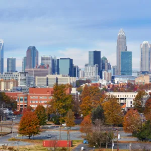 Autumn cityscape of Charlotte, North Carolina with colorful trees and modern skyline under blue sky.