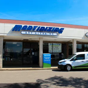 Martinizing Cleaners storefront with branded service van parked outside under clear blue sky in Ann Arbor.