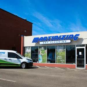 Martinizing Cleaners store front with signage and branded delivery van parked outside on sunny day in Ann Arbor