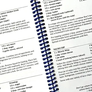 Open spiral-bound cookbook displaying detailed recipes including ingredients and instructions for various dishes
