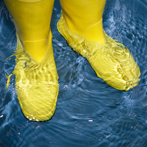 A person wearing yellow rubber boots standing in water