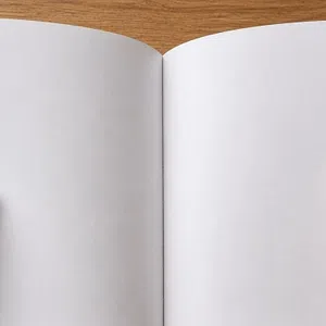 Hands holding open a blank white book showing two empty pages in front of a wooden table background.