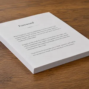 Stack of printed pages titled Foreword placed on wooden surface with readable text about publishing and reflection.