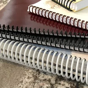 Close-up of stacked spiral-bound books with black, white, and maroon covers.