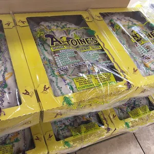 Stacked boxes of Antoine's King Cake with yellow packaging, showcasing traditional Mardi Gras colors and design.