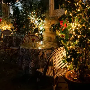 Cozy outdoor cafe seating with patterned chairs and tables lit by warm string lights at night.