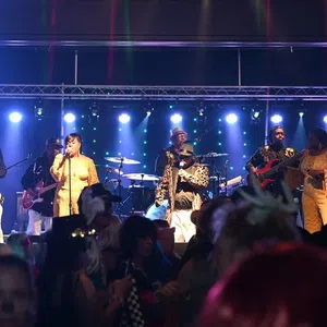 Live band performing on stage with vibrant blue lights and crowd enjoying the music at night event