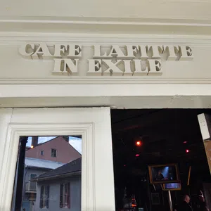 Entrance of Cafe Lafitte in Exile with white wooden doors and reflective glass showing buildings outside.