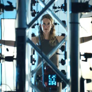 Woman standing inside a 3D scanning rig with arms outstretched surrounded by cameras and lighting panels.