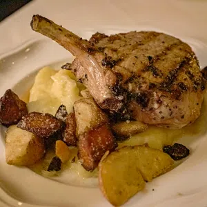 Grilled pork chop served with mashed potatoes and roasted vegetables on a white plate