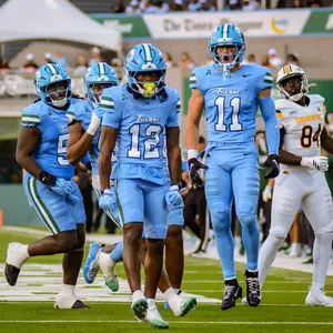Tulane football players in blue uniforms celebrating on the field during a game against Southern University.