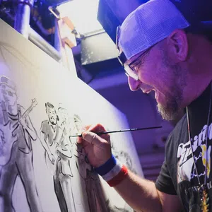 Artist in cap painting a monochrome group portrait on canvas in a studio with focused expression
