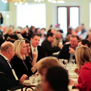 People enjoying a social gathering at a restaurant with conversations and dining in a warm, well-lit atmosphere.