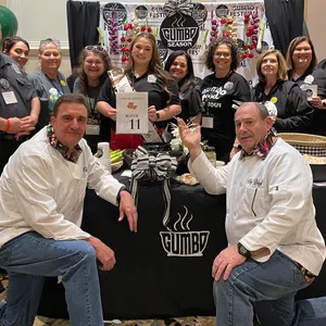 Group of people posing at Gumbo Season Fest booth with festive decorations and promotional materials.