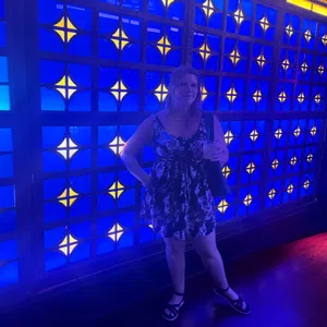 Woman in a floral dress standing in front of a vibrant blue and yellow patterned illuminated wall.