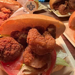 Close-up of fried shrimp po'boy sandwiches with lettuce and tomato on buns on wooden table