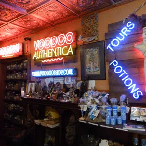 Interior of a voodoo shop with neon signs, shelves of jars, potions, dolls, and mystical items under ornate ceiling tiles.
